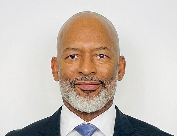 Smiling man wearing a suit against a white background.